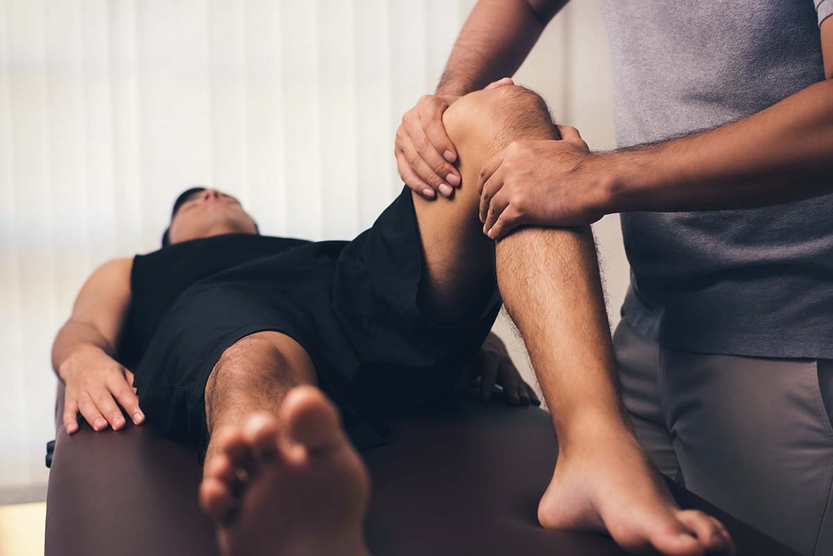 Manual physical therapist treating athlete male patient